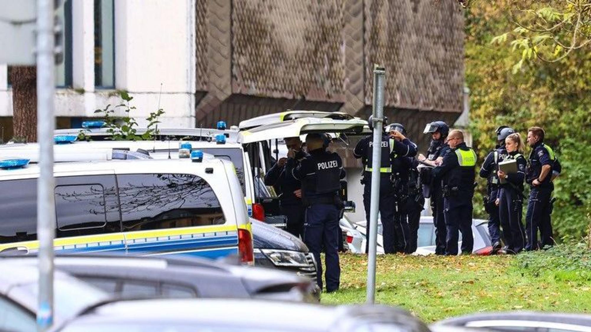 Mehrere Polizeikräfte stehen an Polizeifahrzeugen.