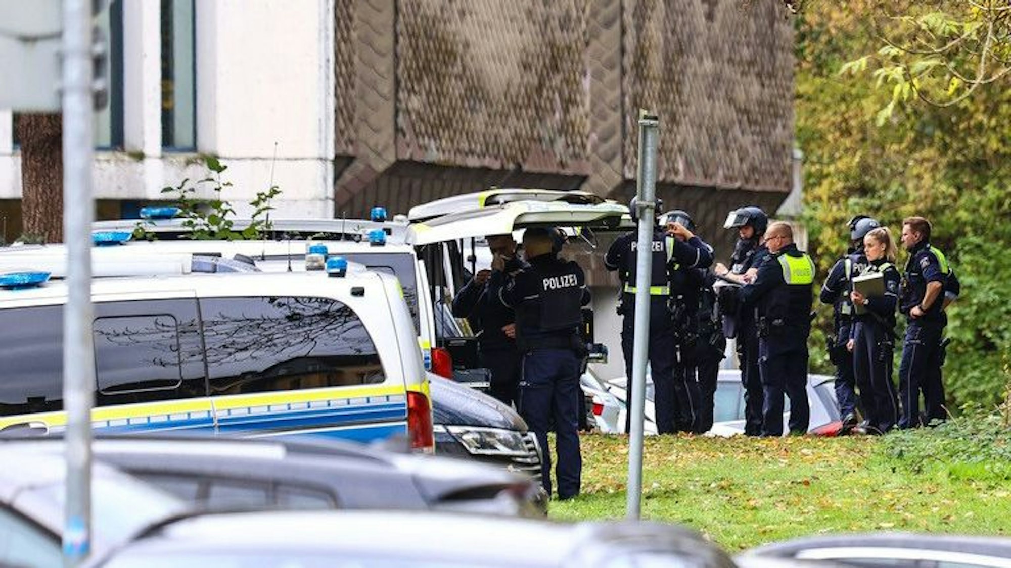 Mehrere Polizeikräfte stehen an Polizeifahrzeugen.