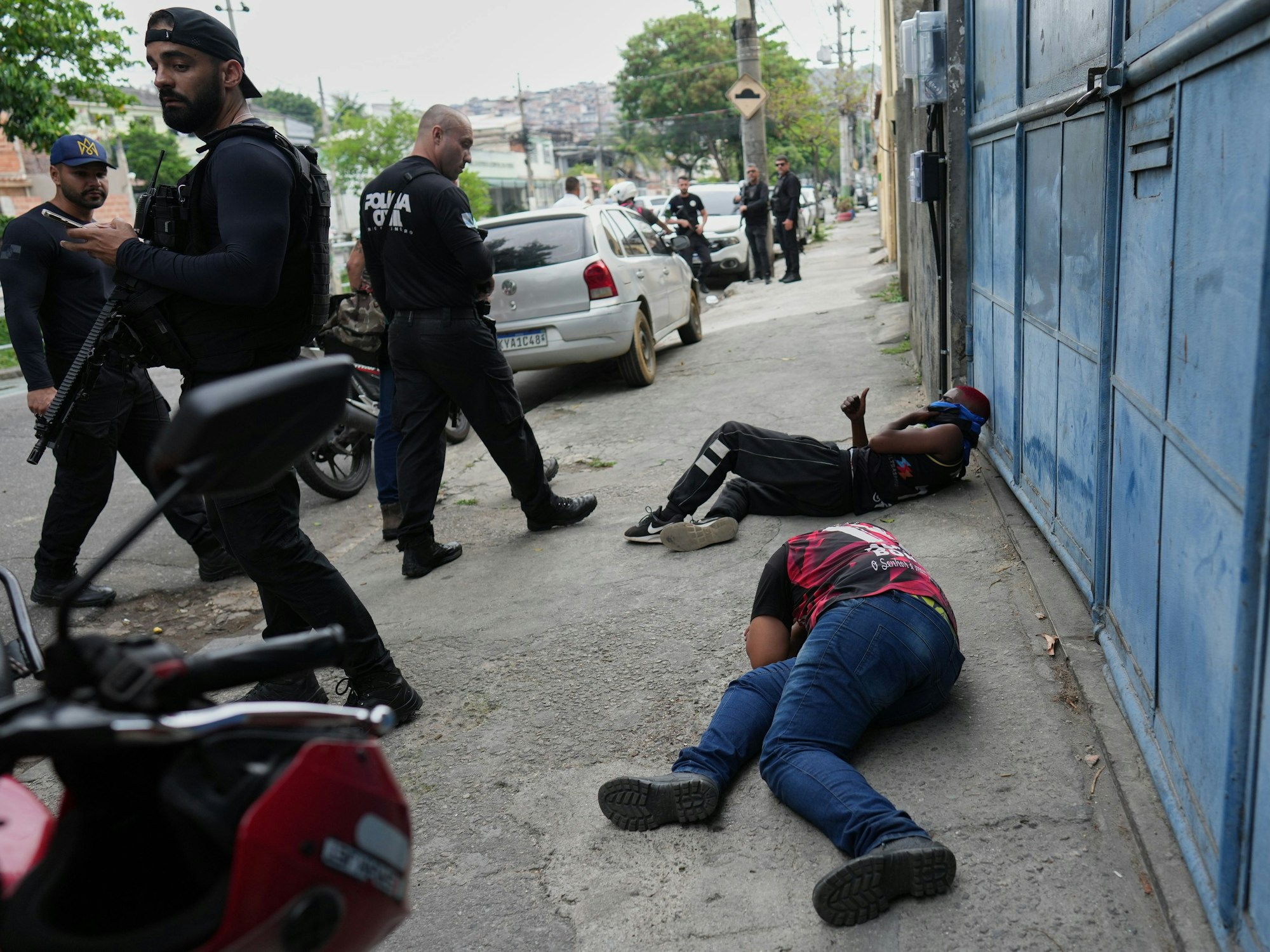 Polizisten stehen vor zwei Männern, die auf dem Boden liegen.