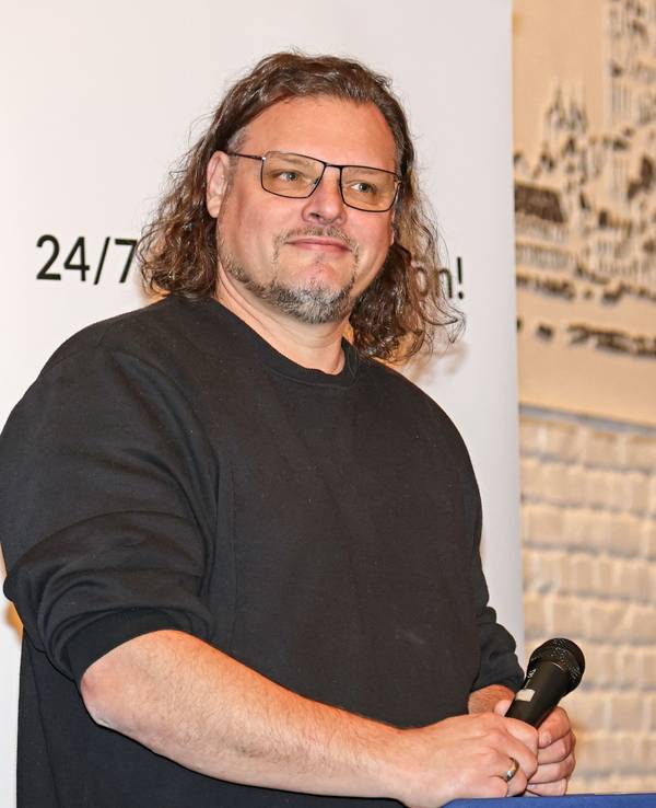 Sänger Micha Hirsch steht am Stehpult, mit dem Mikro in der Hand.