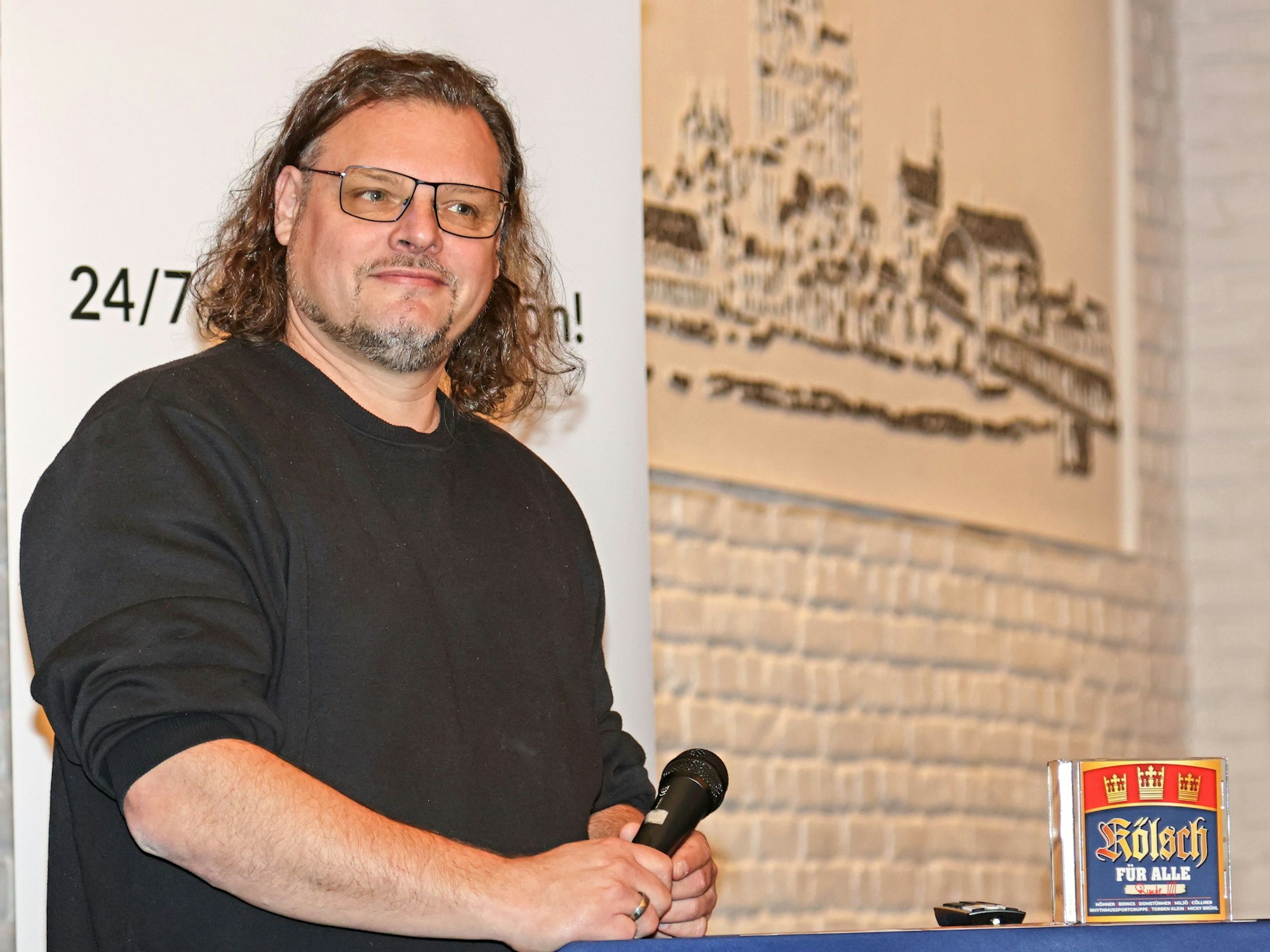 Sänger Micha Hirsch steht am Stehpult, mit dem Mikro in der Hand.