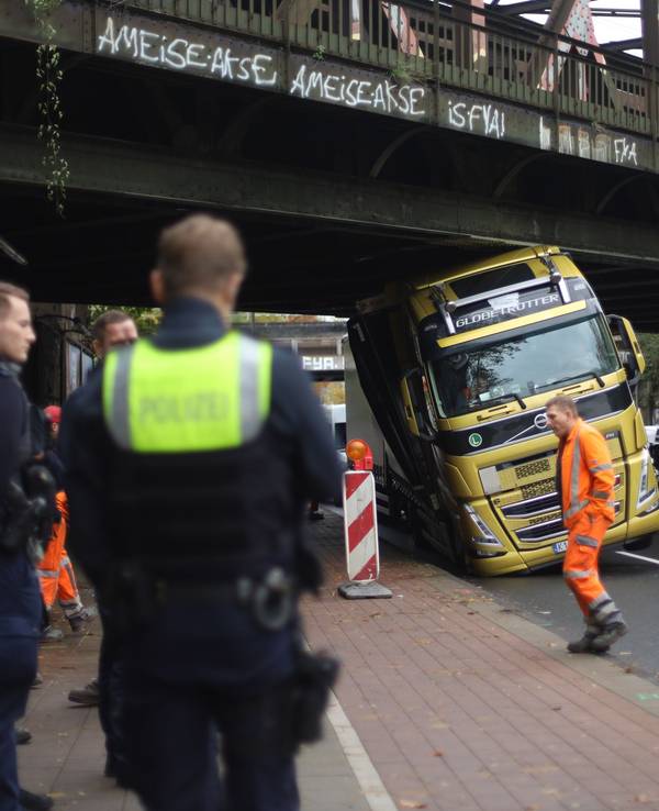 Ein Lkw hängt mit dem Führerhaus unter einer Brücke fest.