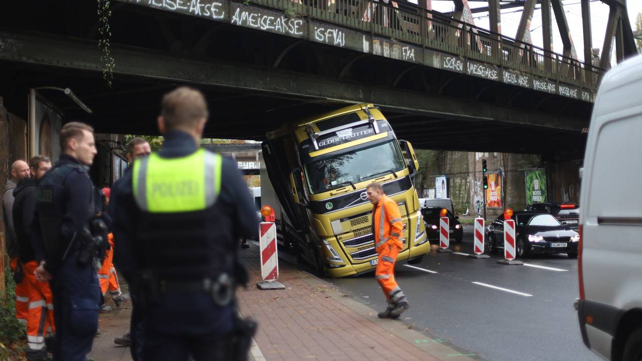 Ein Lkw hängt mit dem Führerhaus unter einer Brücke fest.
