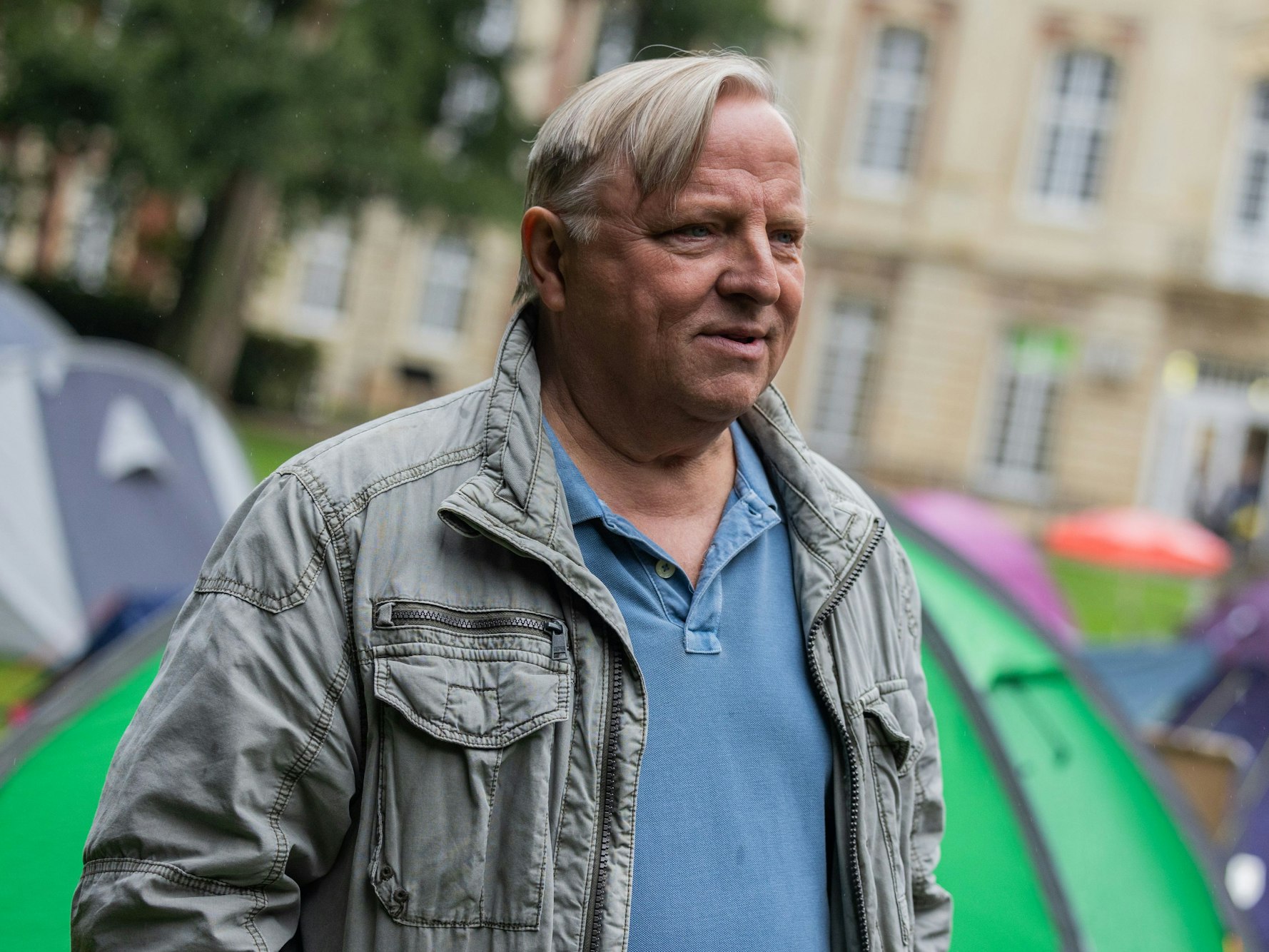 Schauspieler Axel Prahl steht an einem Drehset vor dem Schloss.