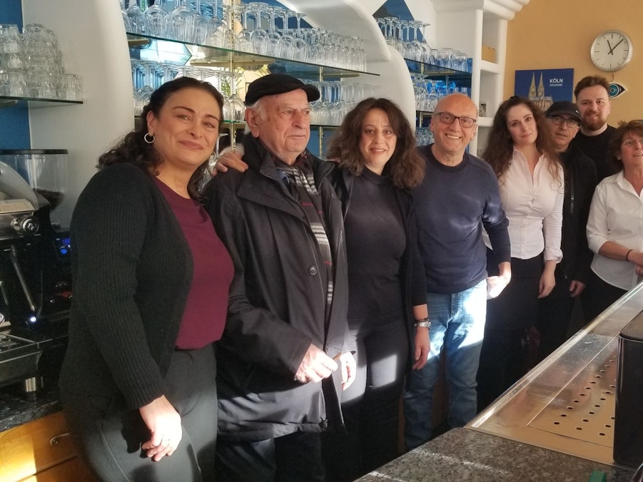 Vier Frauen und vier Männer sehen hinter einem Tresen in einem Restaurant.