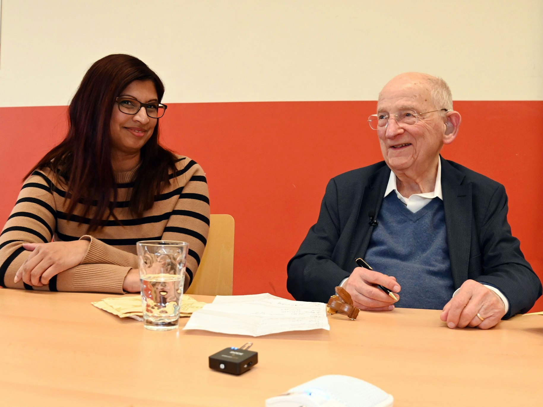 Ein alter Herr und eine junge Frau sitzen am Tisch und unterhalten sich.