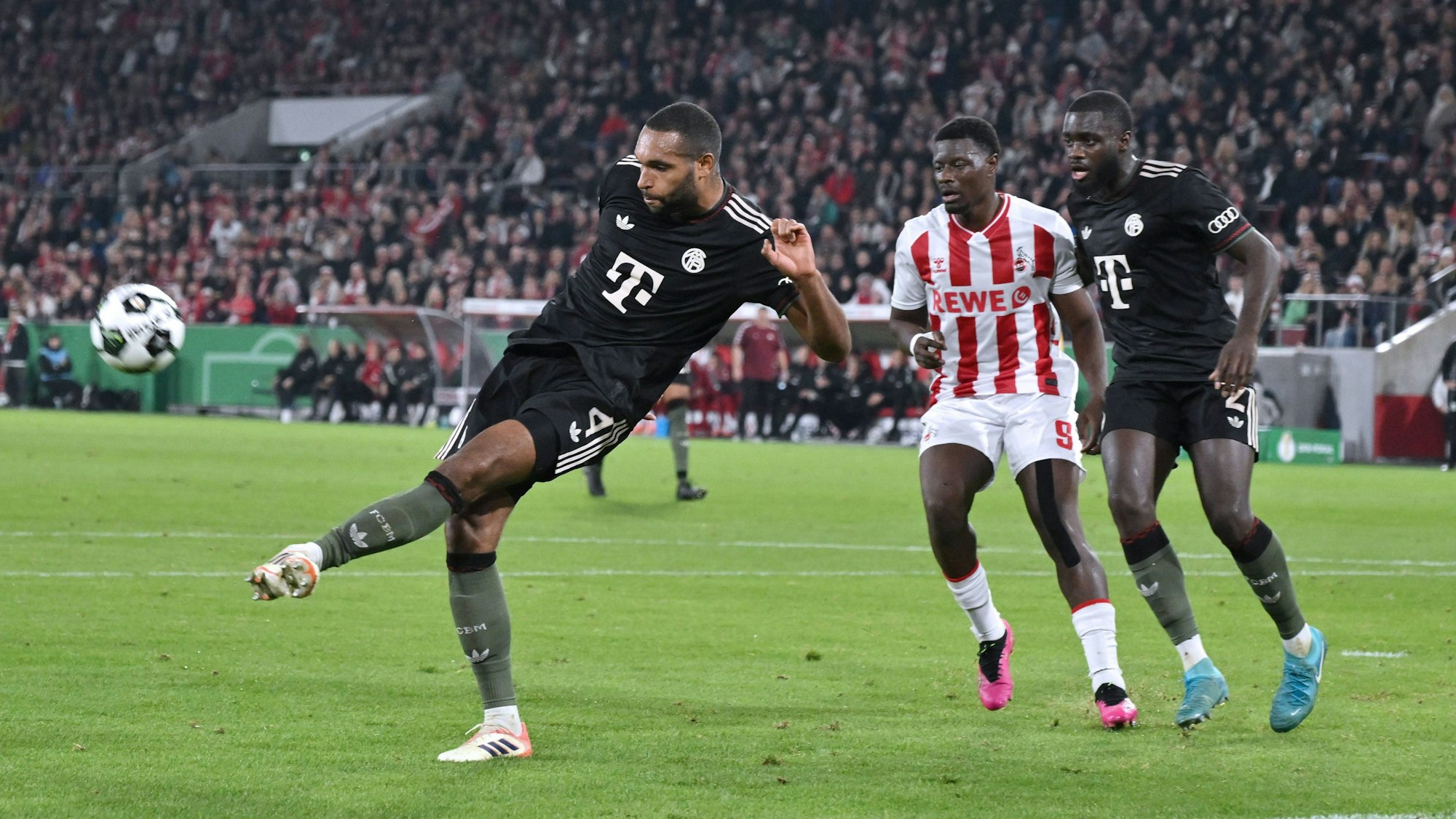 Jonathan Tah (Bayern München), Ragnar Ache (1. FC Köln), Dayot Upamecano (Bayern München) kämpfen im Strafraum um den Ball.