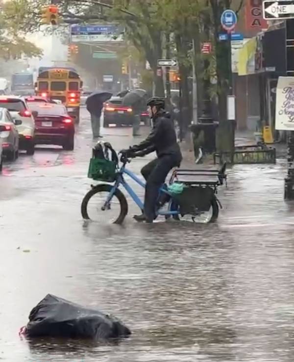 Ein Radfahrer fährt während eines Regenschauers in New York durch die Fluten.