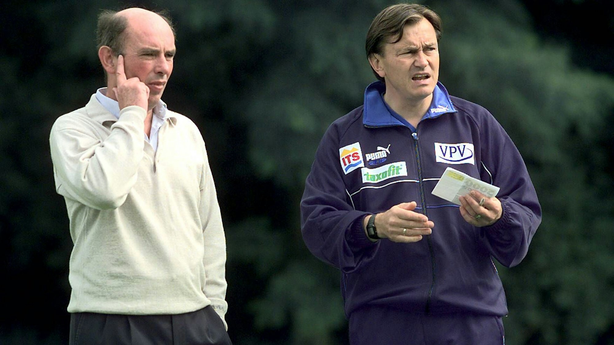 Ewald Lienen steht neben Hannes Linßen auf dem Trainingsplatz.