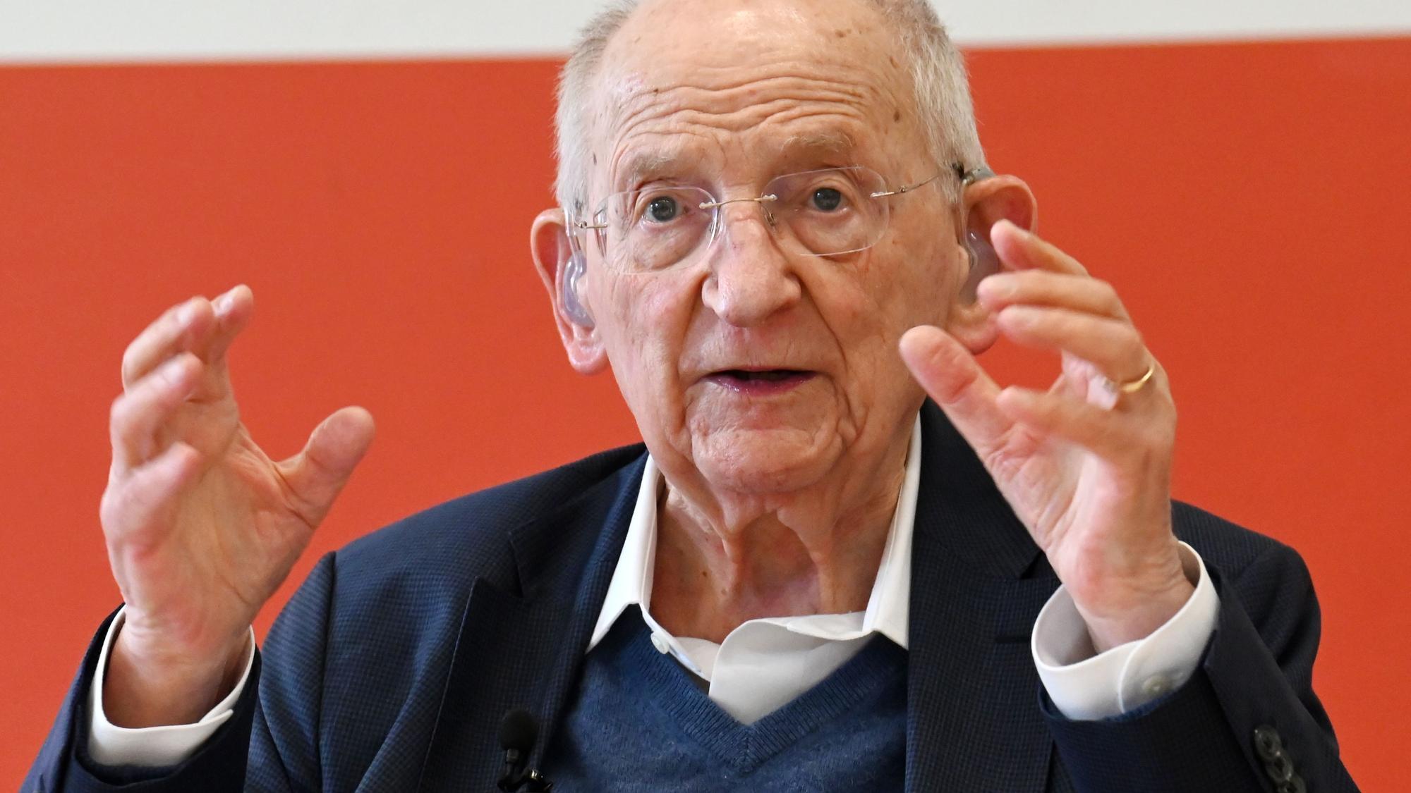 Ein alter Herr mit Hörgerät und weißem Haar gestikuliert und redet