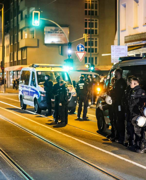 Einsatzkräfte stehen bei Nacht vor zwei Einsatzfahrzeugen auf einer Straße.