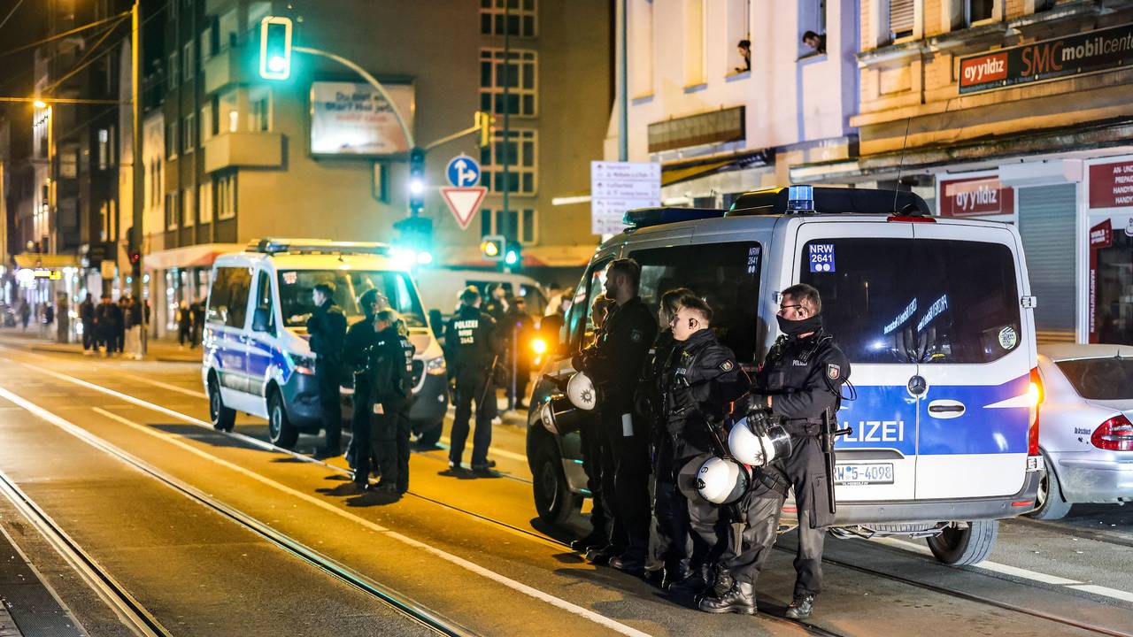 Einsatzkräfte stehen bei Nacht vor zwei Einsatzfahrzeugen auf einer Straße.