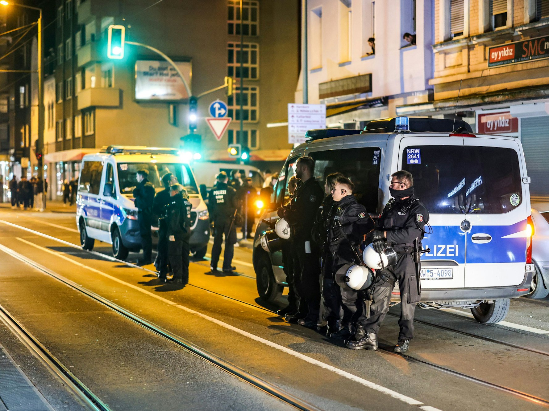 Einsatzkräfte stehen bei Nacht vor zwei Einsatzfahrzeugen auf einer Straße.