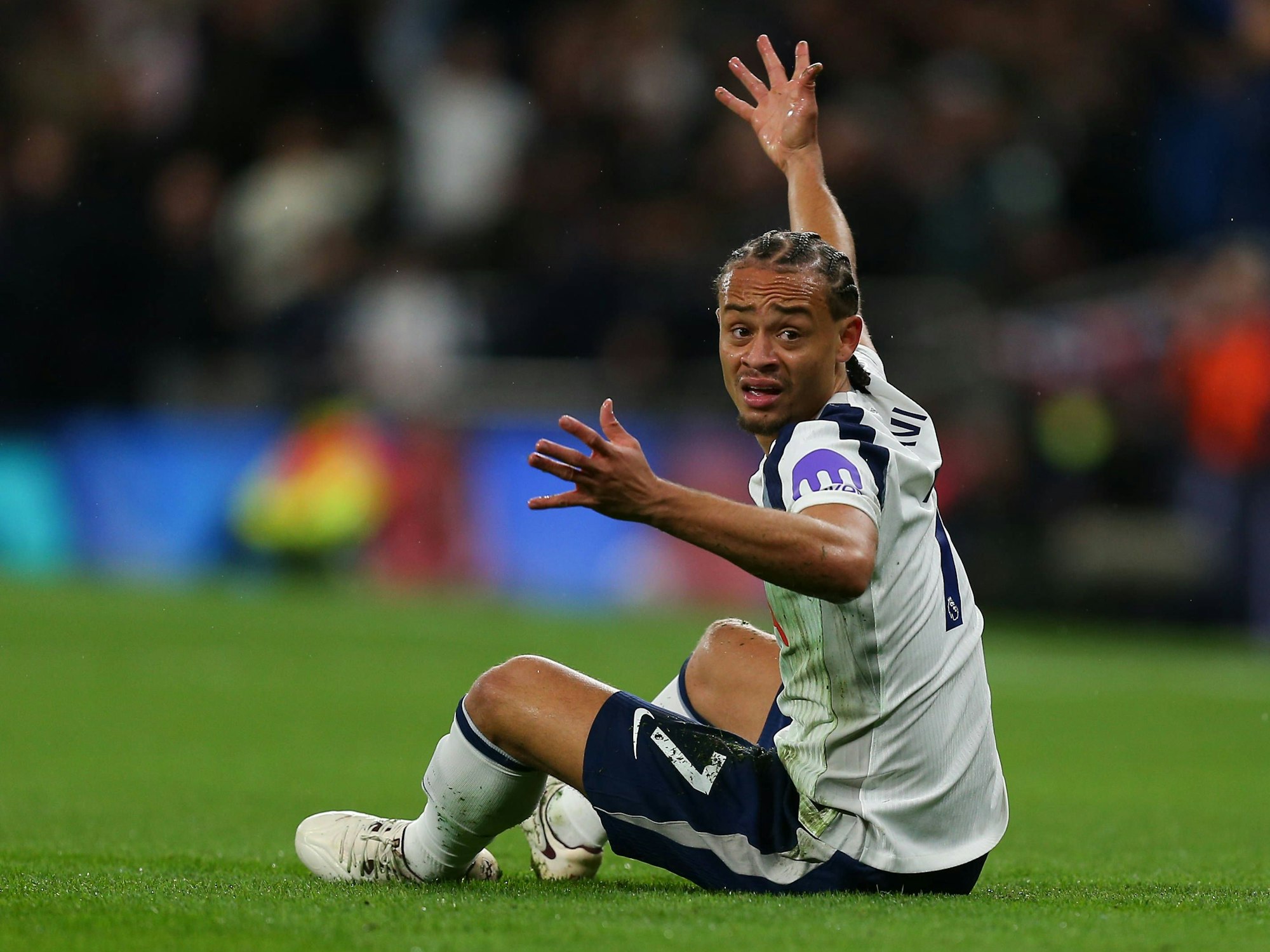 Xavi Simons sitzt auf dem Rasen und gestikuliert.