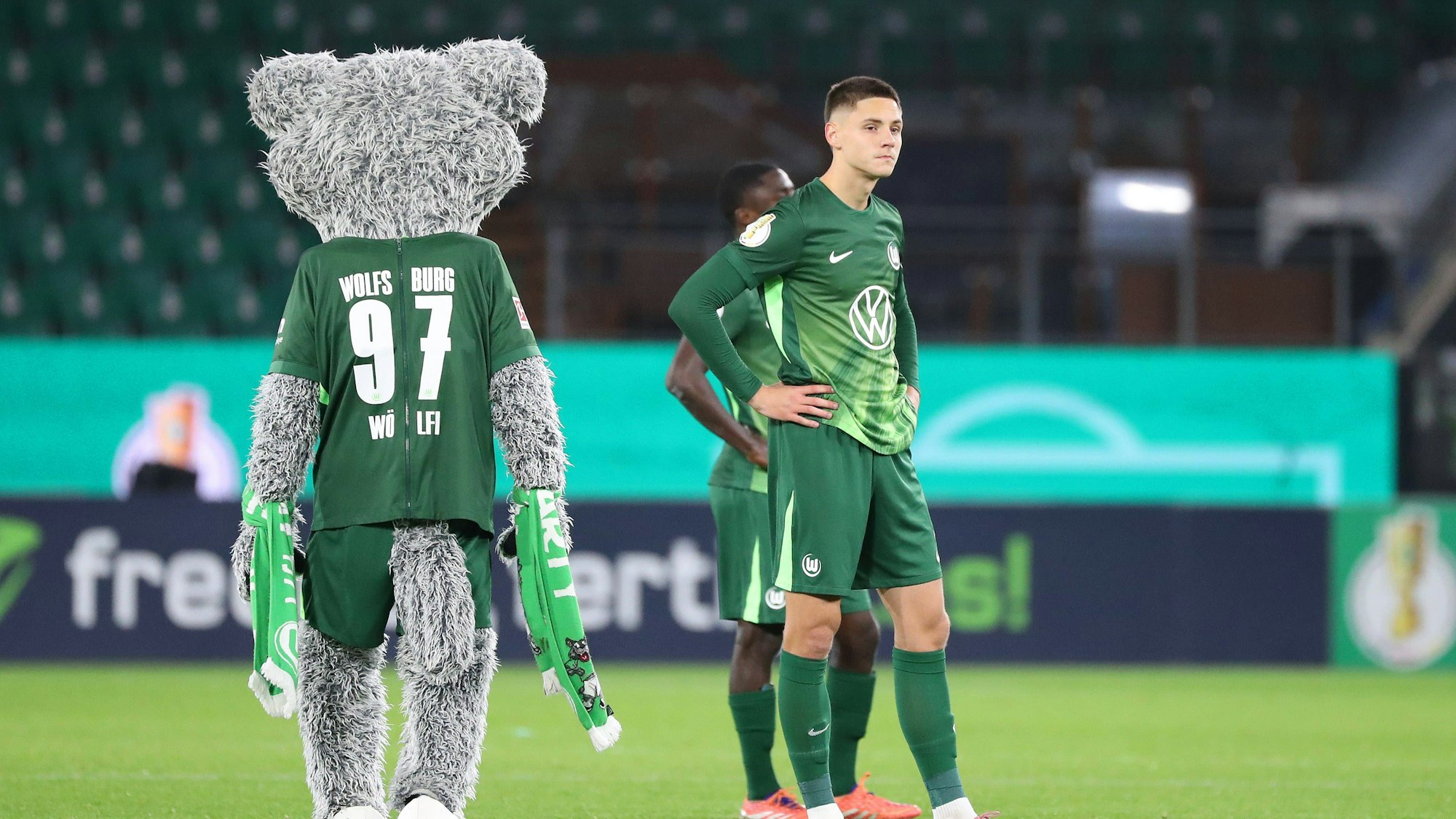 Bence Dardai steht neben dem Maskottchen des VfL Wolfsburg und schaut ratlos.