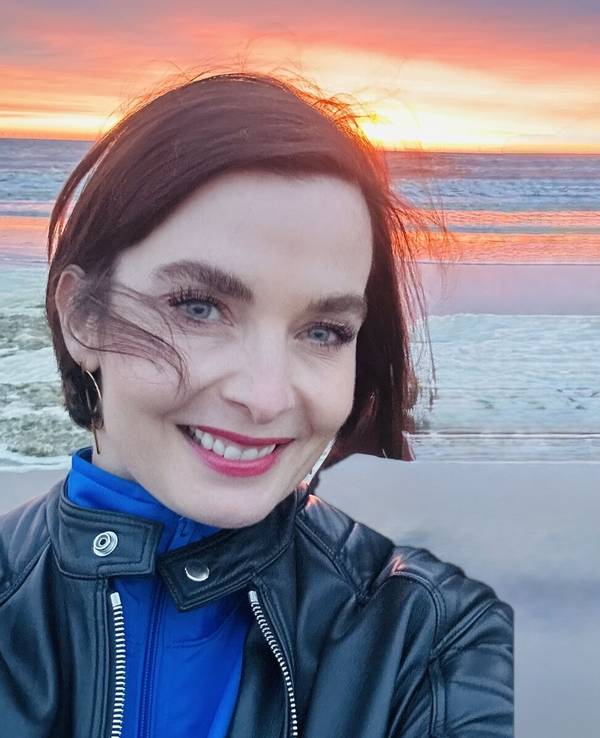Eine Frau steht vor einem Meer und macht ein Selfie.