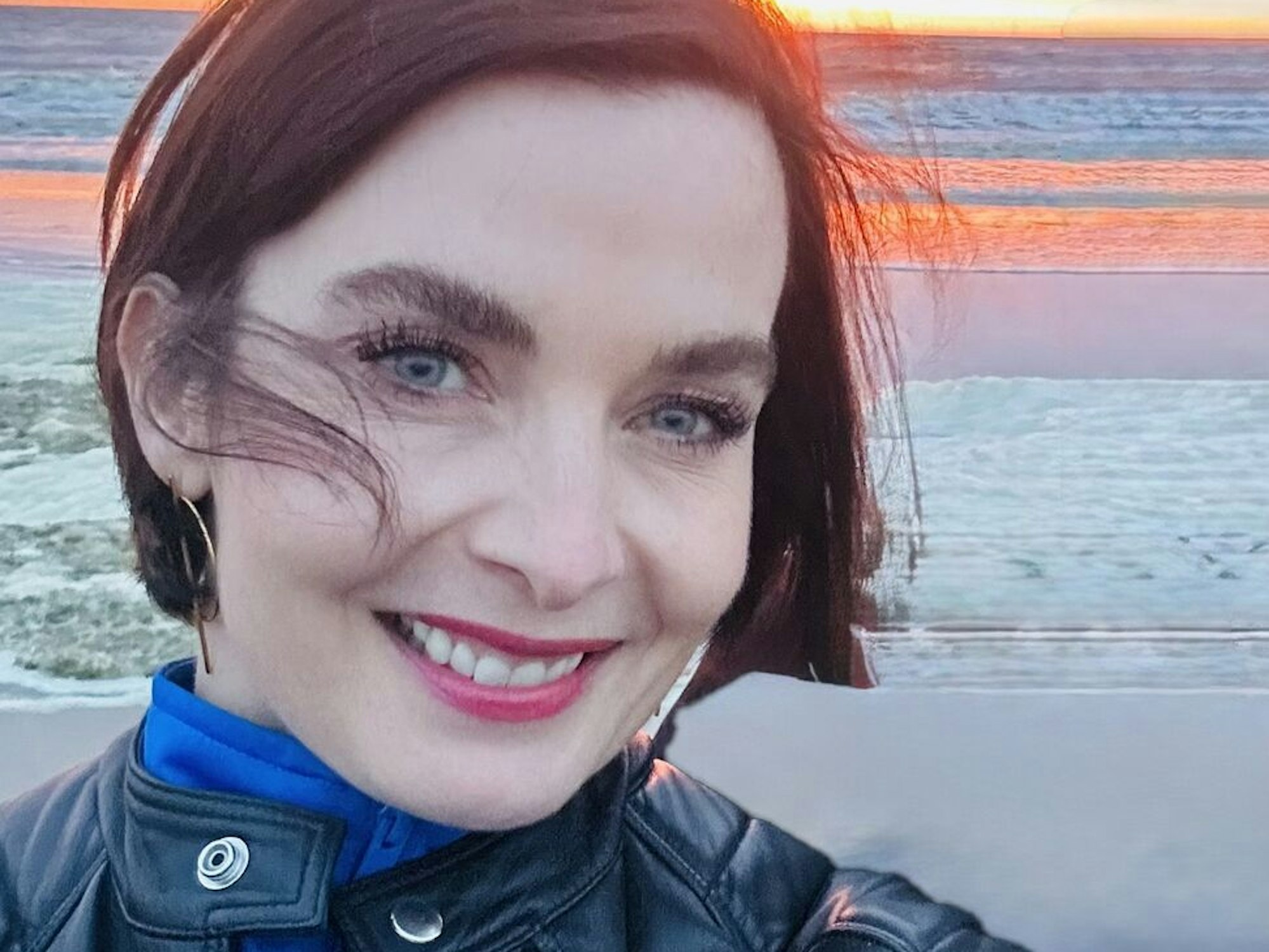 Eine Frau steht vor einem Meer und macht ein Selfie.