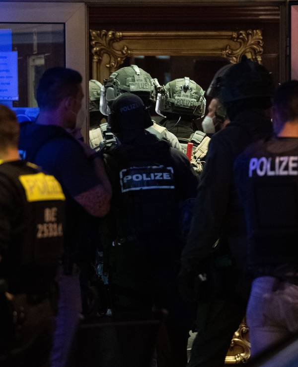 Polizeikräfte und SEK-Kräfte stehen vor einem Gebäude