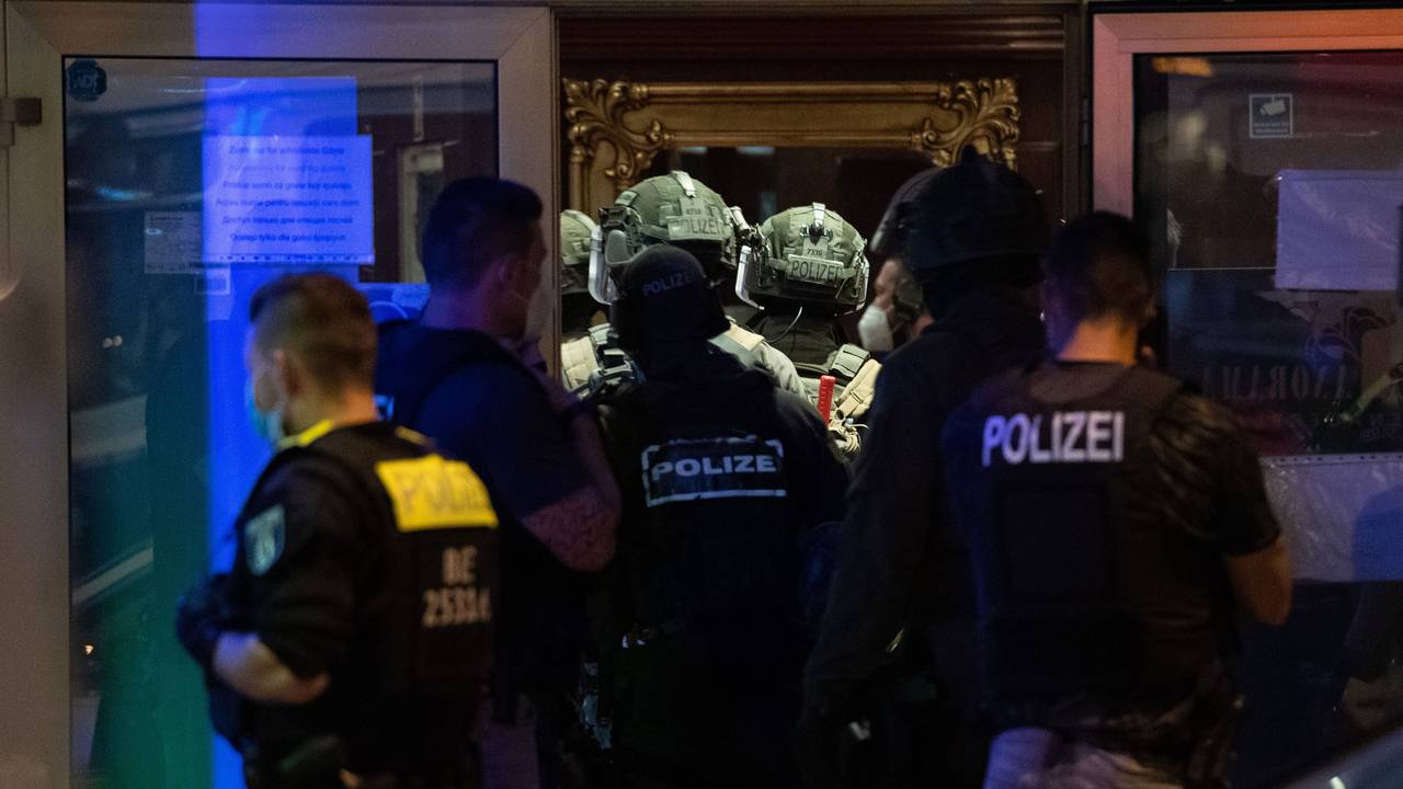 Polizeikräfte und SEK-Kräfte stehen vor einem Gebäude