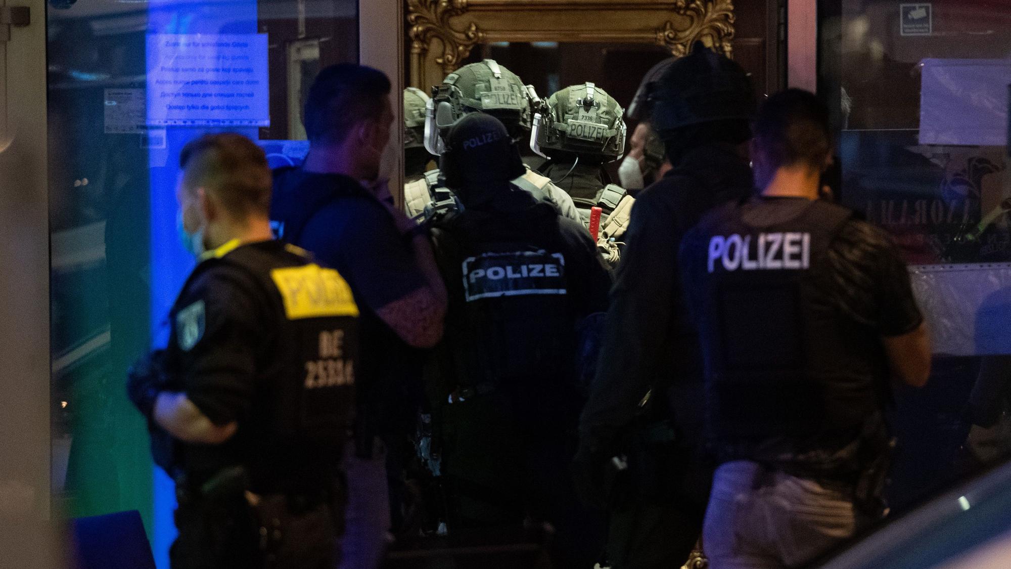 Polizeikräfte und SEK-Kräfte stehen vor einem Gebäude