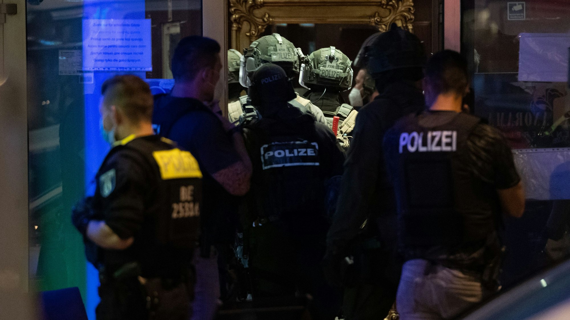 Polizeikräfte und SEK-Kräfte stehen vor einem Gebäude