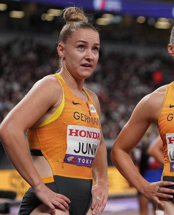 Sophia Junk und Gina Lückenkemper schauen kurz nach einem Wettkampf nach oben auf den Bildschirm im Stadion.