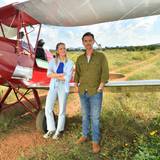 Szene aus dem ZDF-Traumschiff: Sophia Berg (Valentina Pahde) und Max Parger (Florian Silbereisen) stehen vor einem roten Propeller-Flugzeug in der afrikanischen Savanne