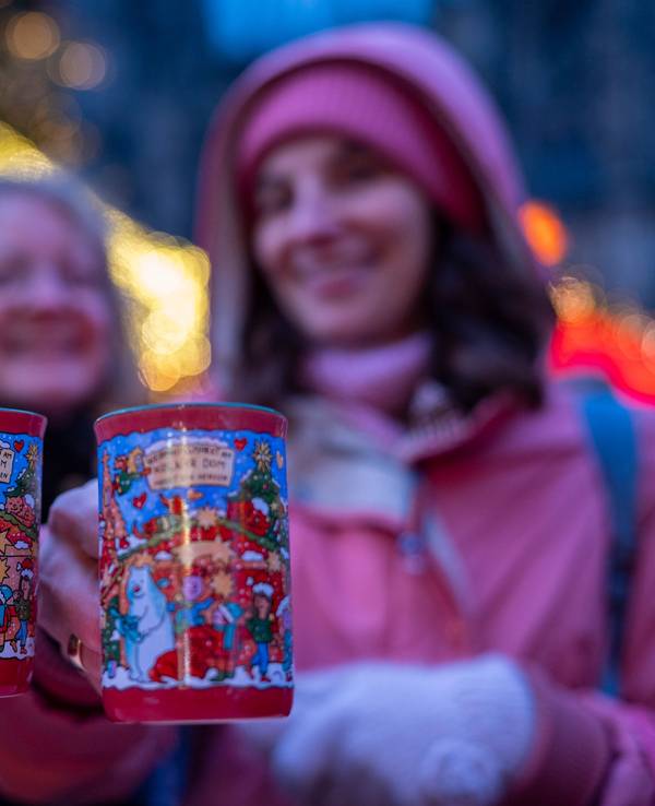 Zwei Frauen halten je eine rote Tasse Glühwein in der Hand.
