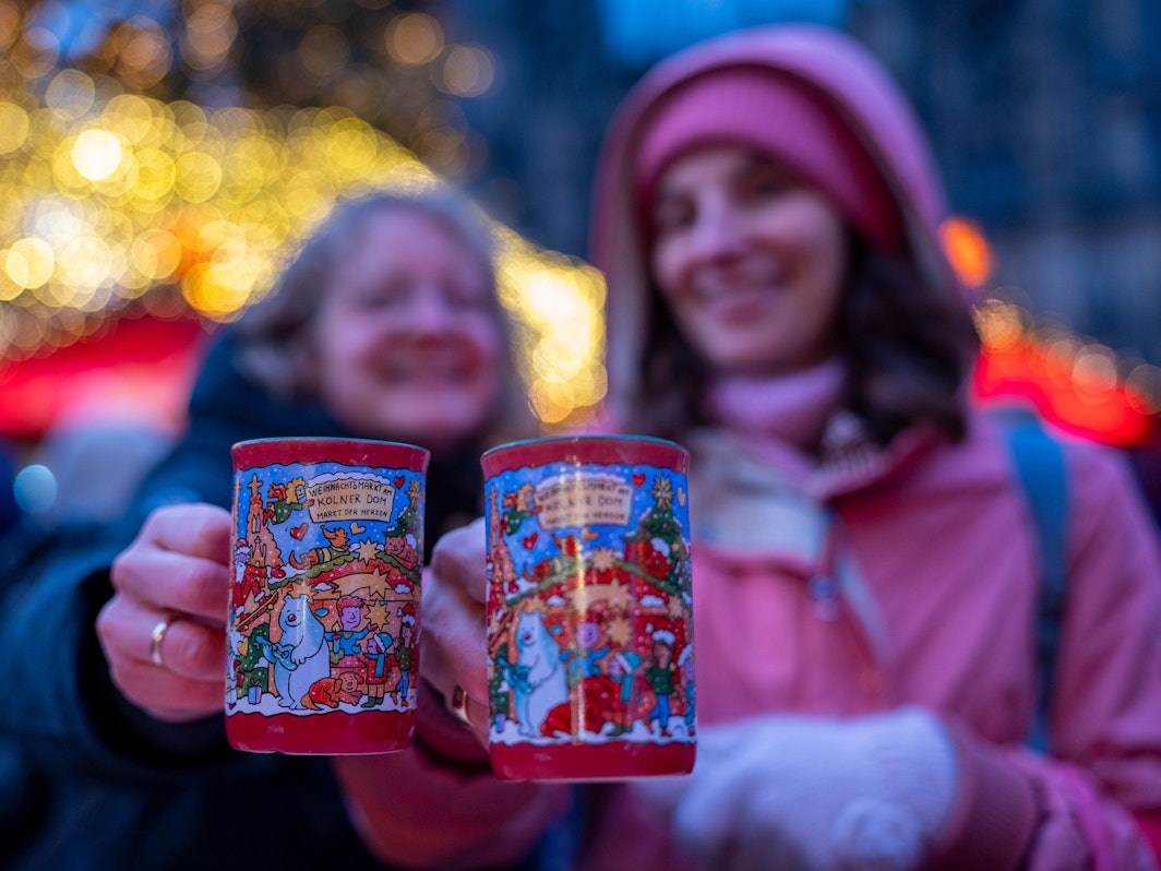 Zwei Frauen halten je eine rote Tasse Glühwein in der Hand.