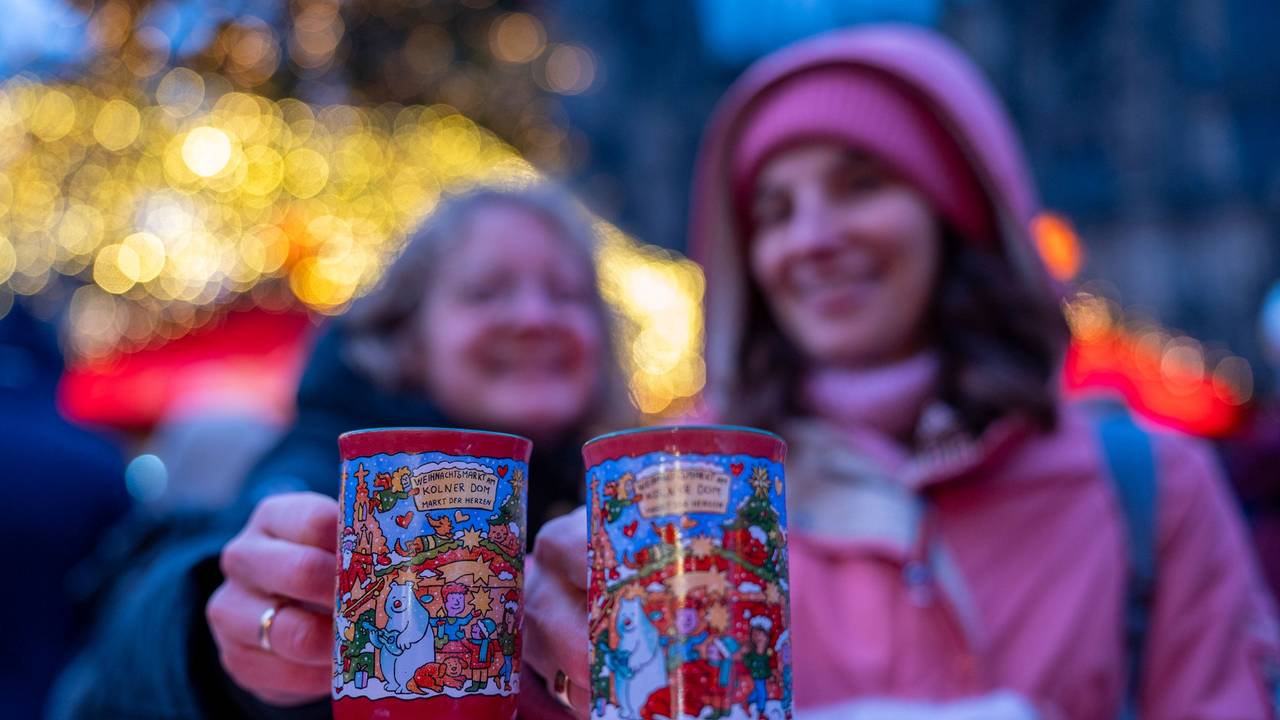 Zwei Frauen halten je eine rote Tasse Glühwein in der Hand.