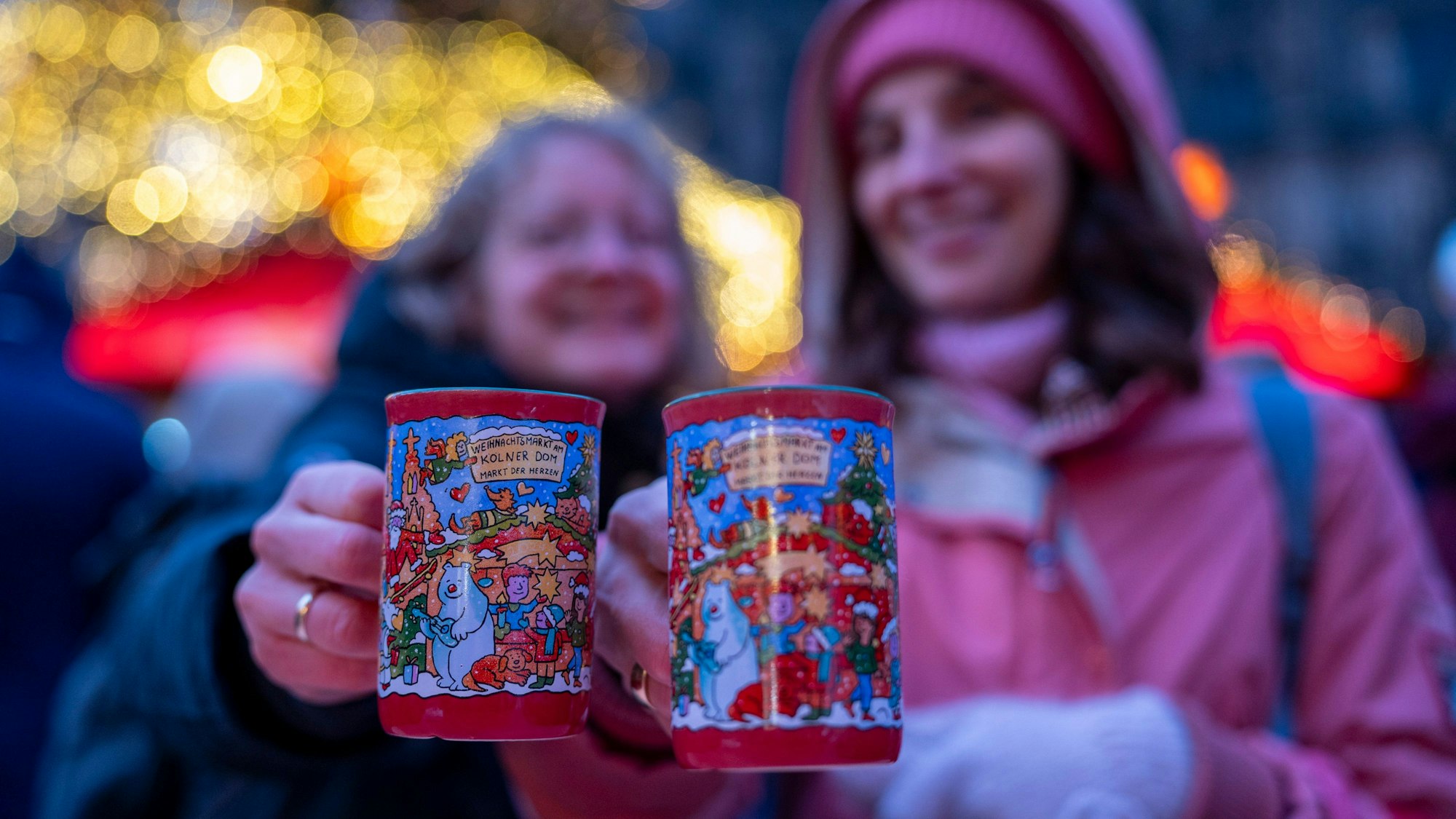 Zwei Frauen halten je eine rote Tasse Glühwein in der Hand.