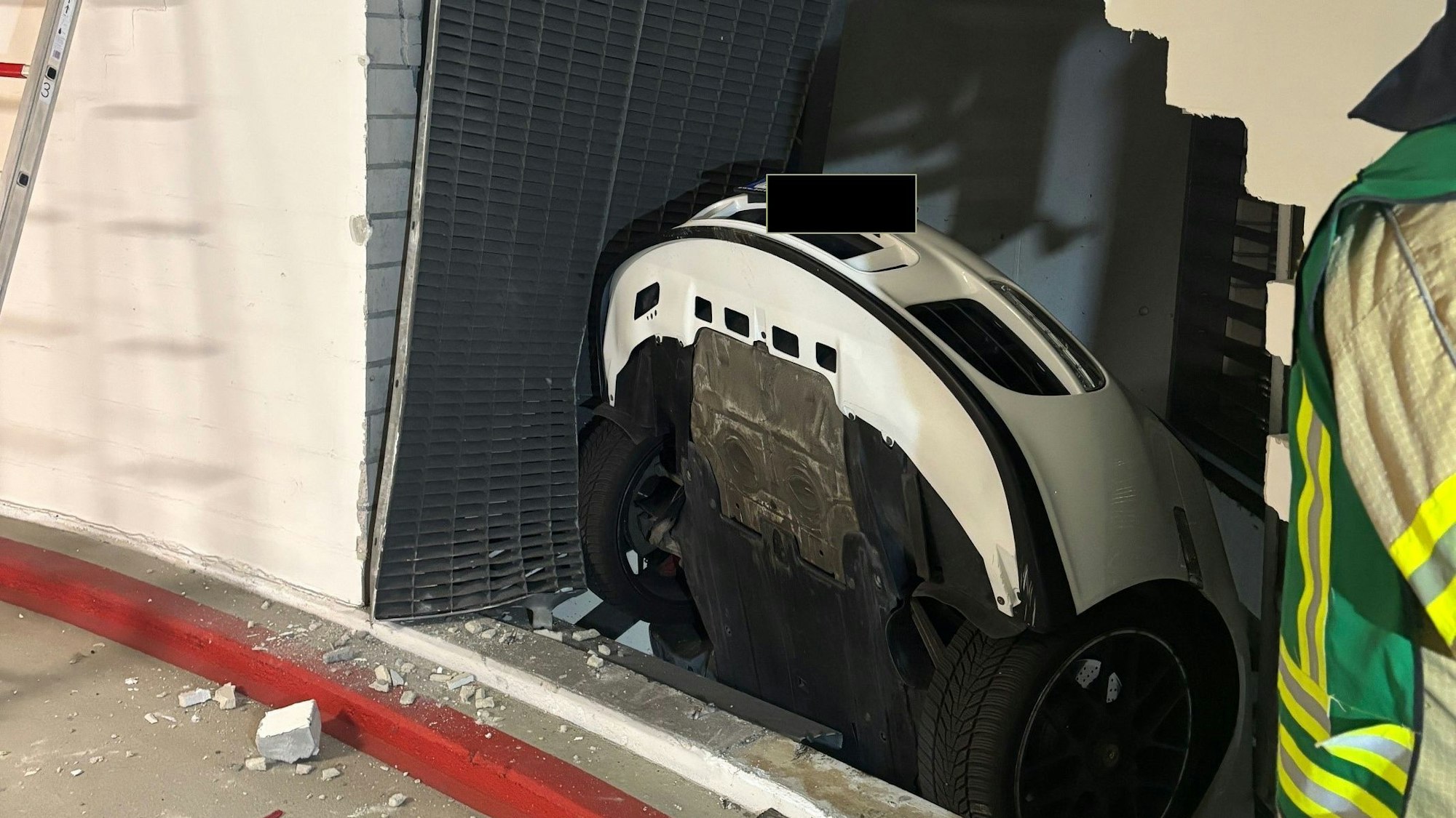 Ein Porsche steckt mit dem Heck in einem Loch in einer Betonwand in einer Tiefgarage.