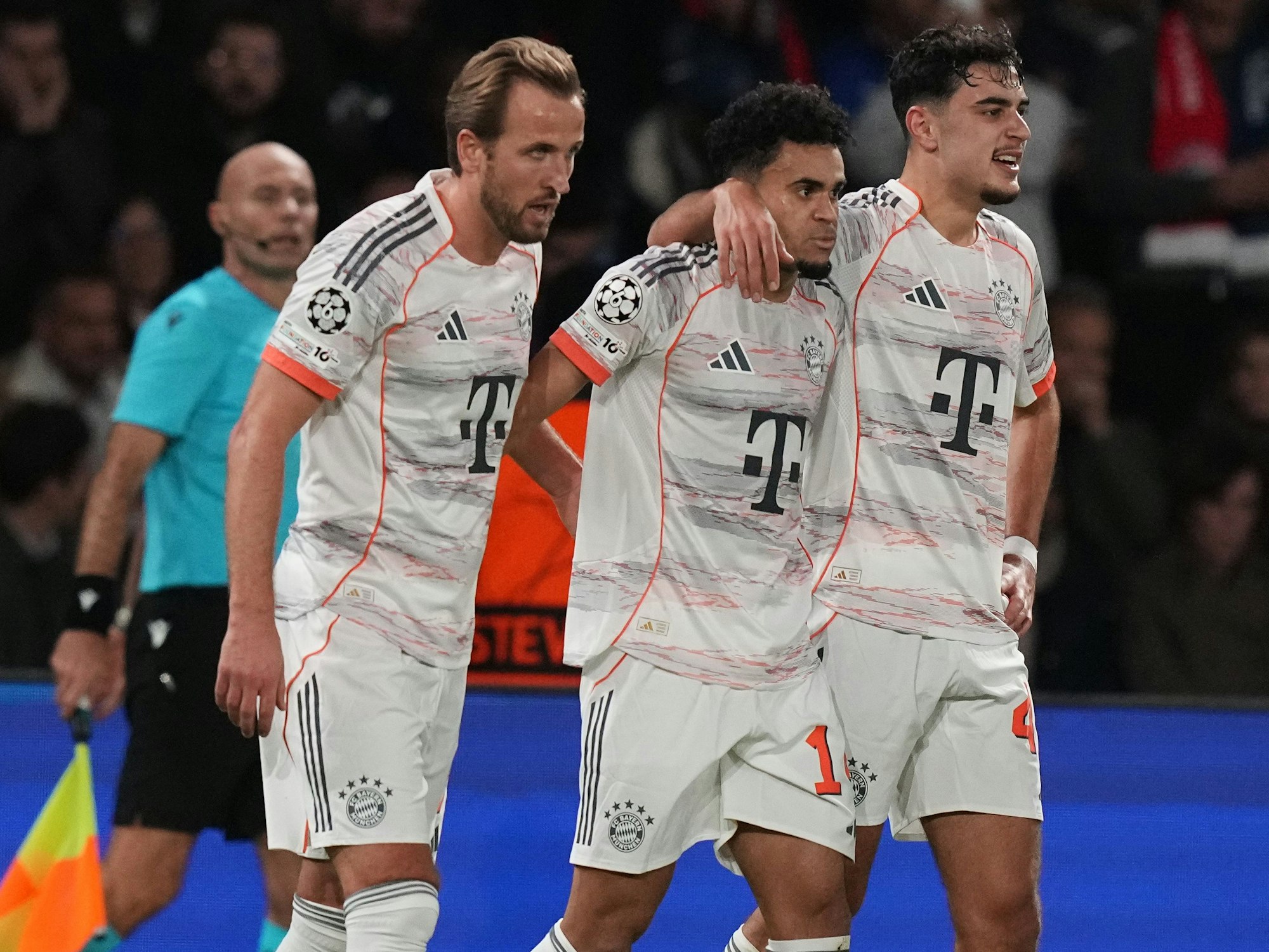 Harry Kane, Luis Diaz und Aleksandar Pavlovic gehen Arm in Arm über den Platz.