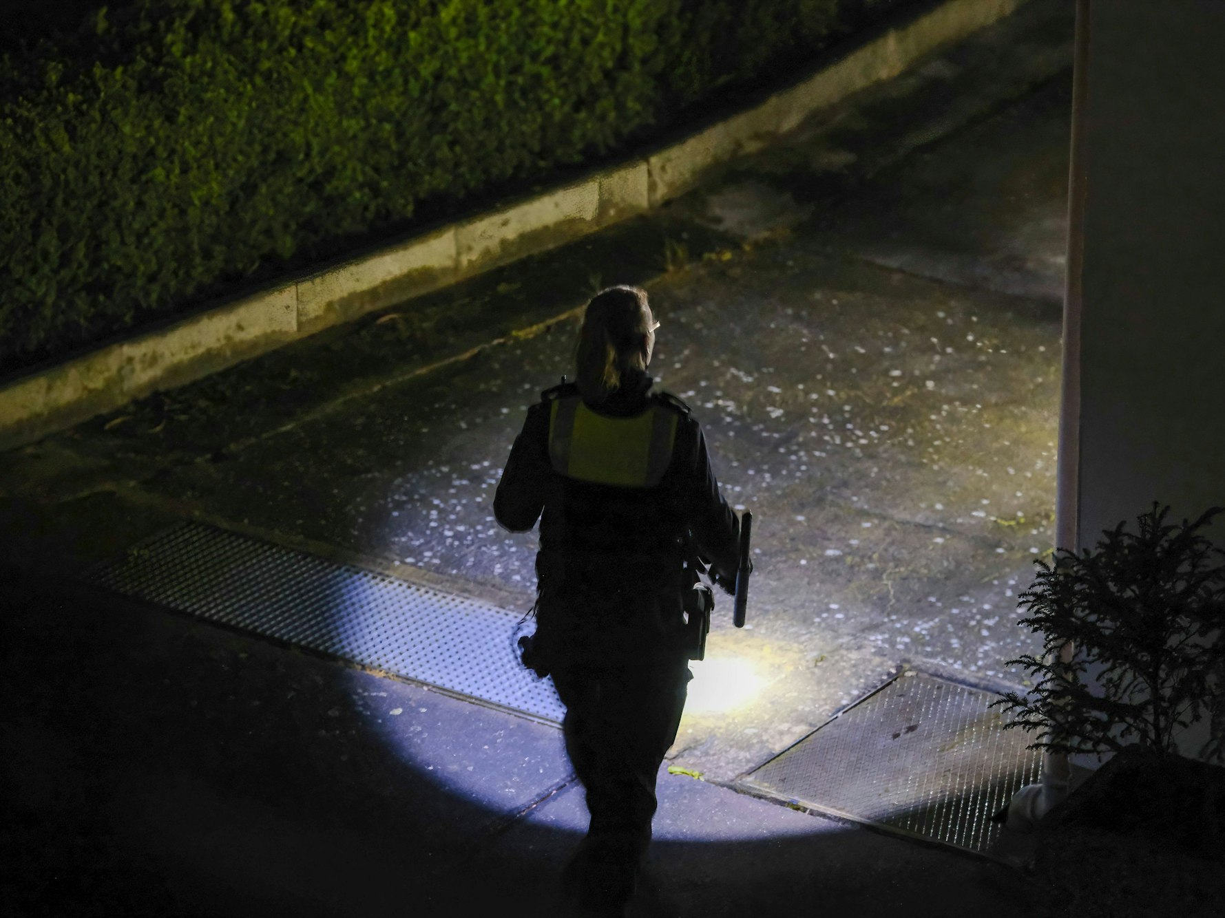 Eine Polizistin sucht mit einer Taschenlampe die Gegend ab.