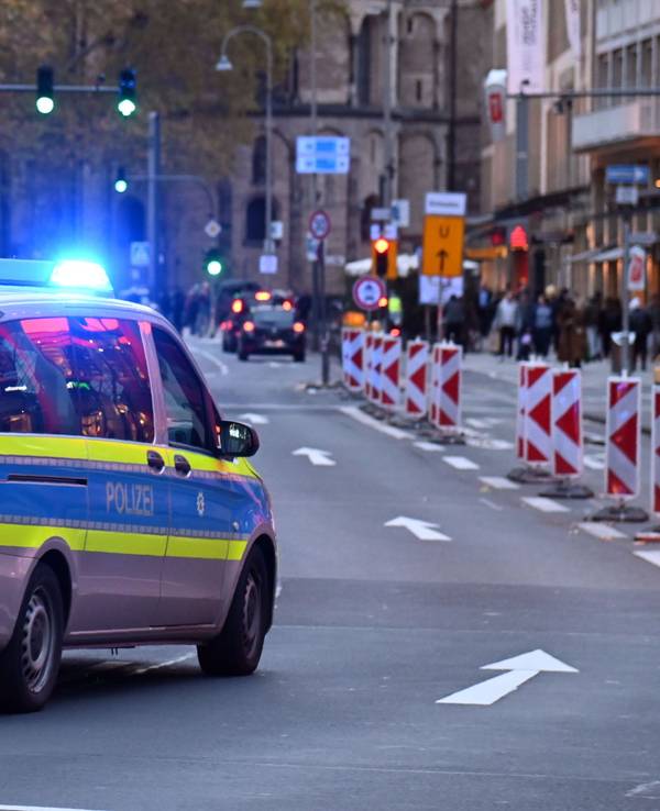 Ein Polizeiauto rast mit Blaulicht am Kölner Neumarkt an Passanten vorbei.
