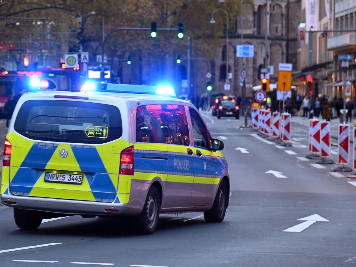 Ein Polizeiauto rast mit Blaulicht am Kölner Neumarkt an Passanten vorbei.