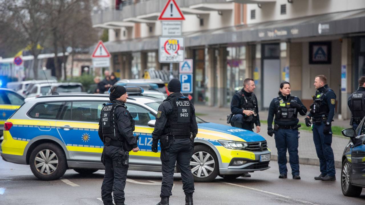 Polizistinnen und Polizisten stehen neben einem Polizeiauto auf der Straße.