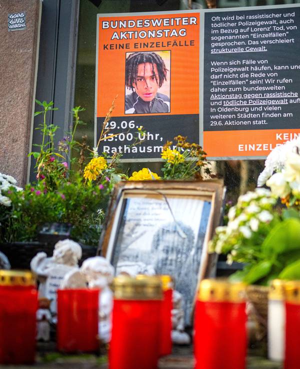 An einem Tatort stehen Fotos des Opfers und Kerzen, liegen Blumen.