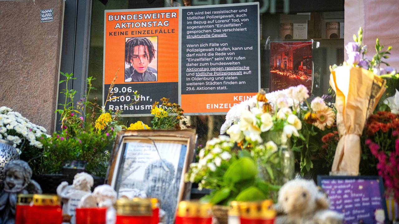 An einem Tatort stehen Fotos des Opfers und Kerzen, liegen Blumen.