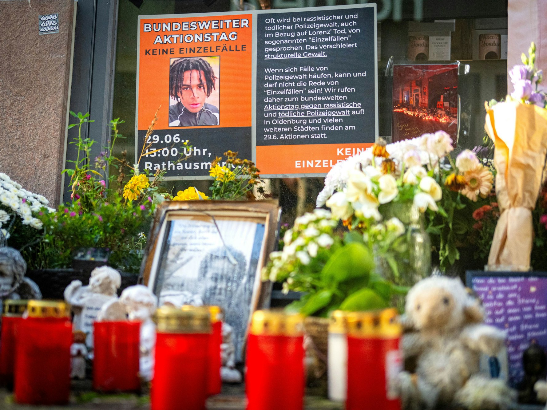 An einem Tatort stehen Fotos des Opfers und Kerzen, liegen Blumen.