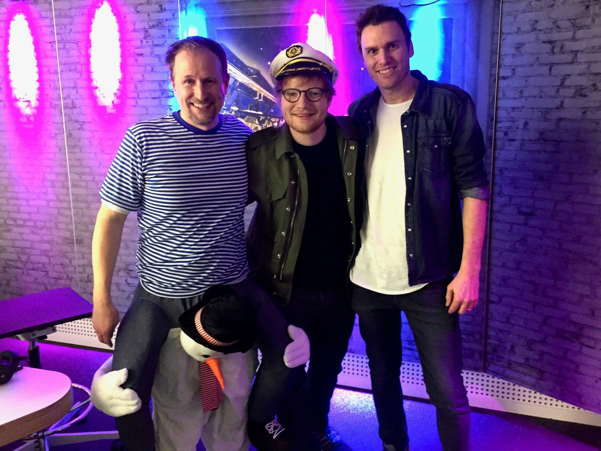 Olli Briesch und Michael Imhof stehen mit Ed Sheeran im Studio.