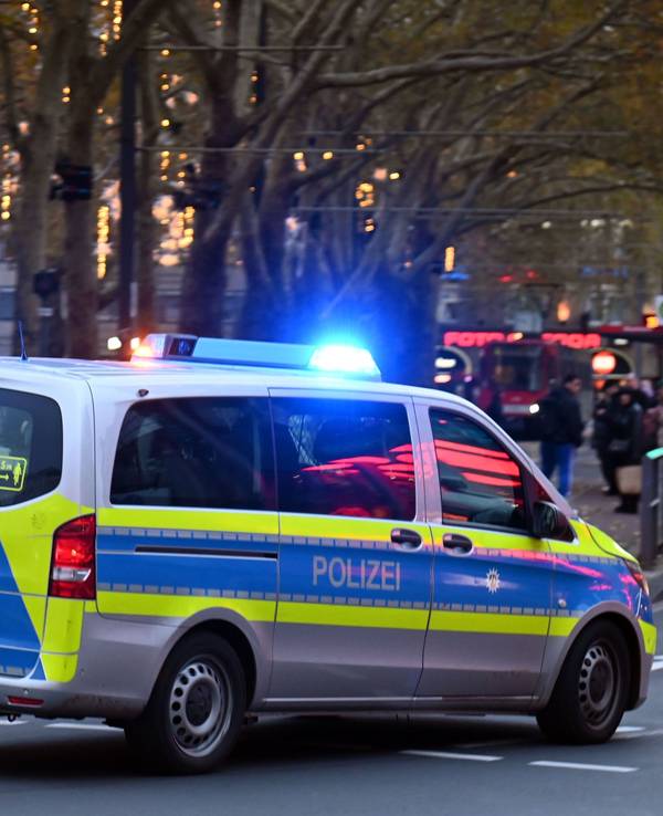 Ein Polizeiauto rast mit Blaulicht am Neumarkt an Passanten vorbei.