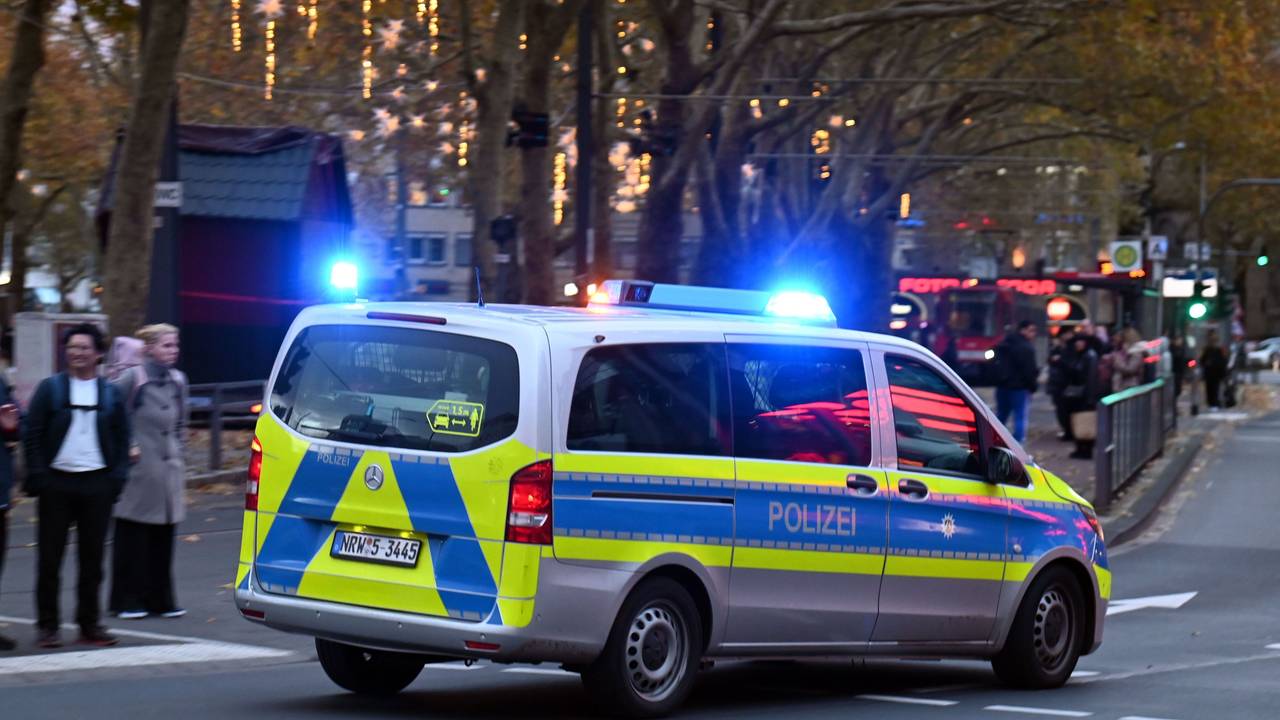 Ein Polizeiauto rast mit Blaulicht am Neumarkt an Passanten vorbei.