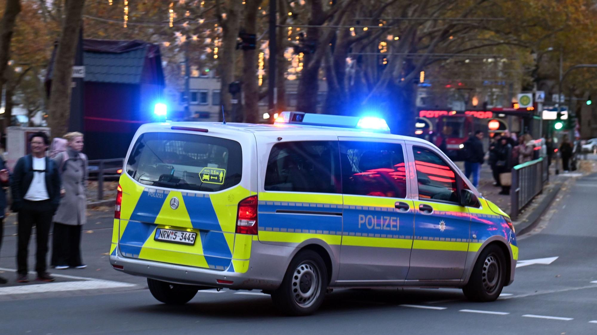 Ein Polizeiauto rast mit Blaulicht am Neumarkt an Passanten vorbei.