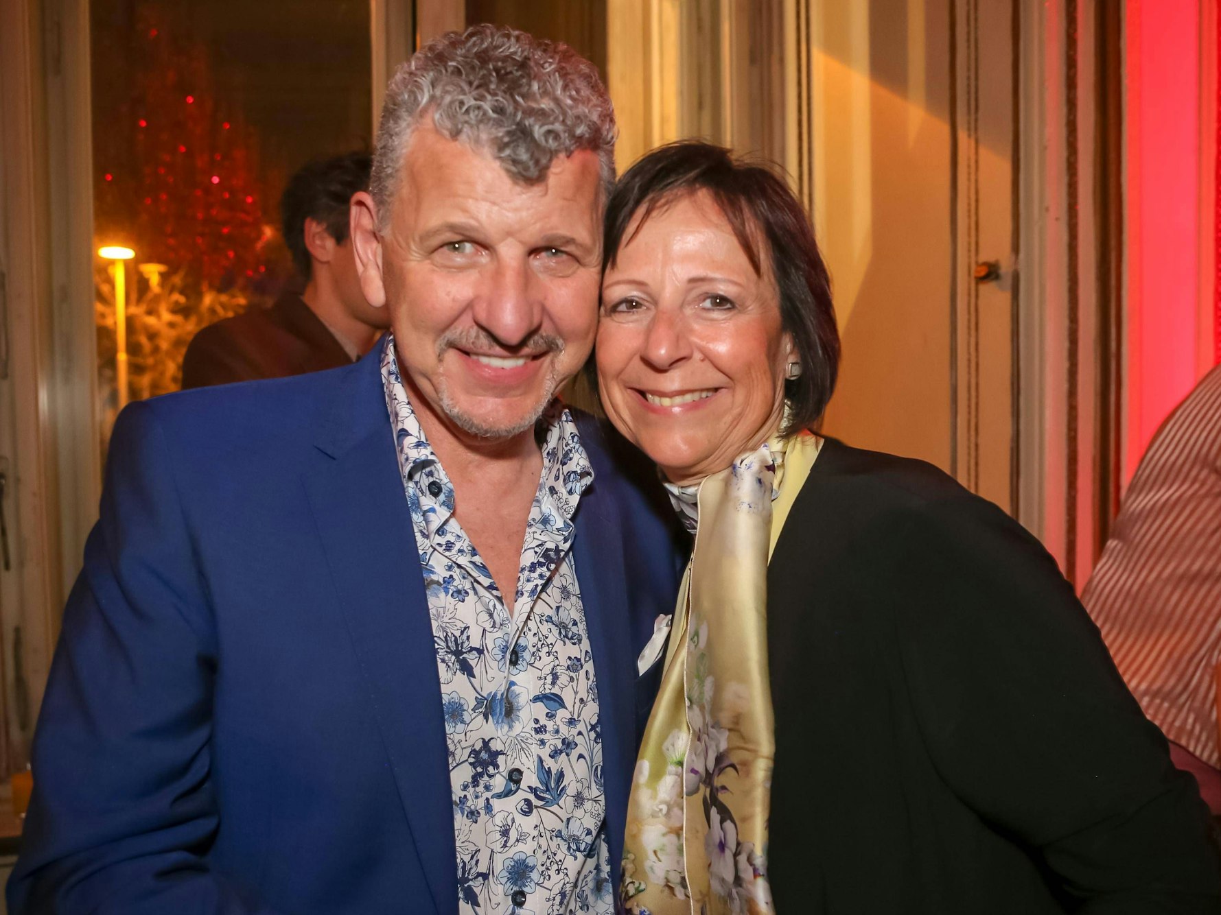 Ein Mann und eine Frau, beide mittleren Alters, lächeln in die Kamera.