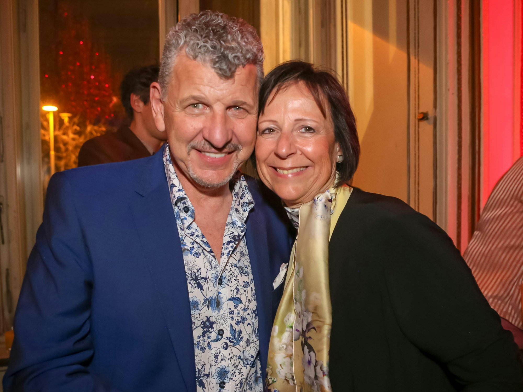 Ein Mann und eine Frau, beide mittleren Alters, lächeln in die Kamera.