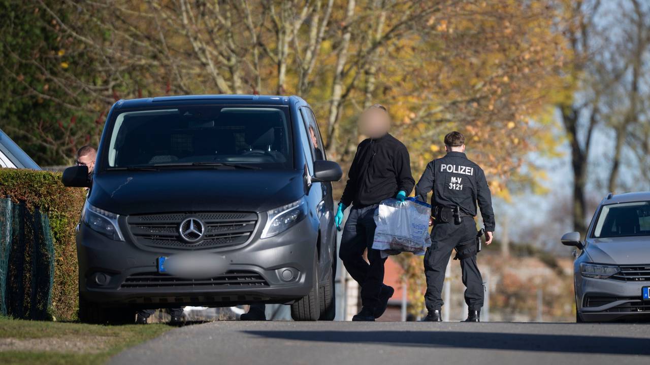 Ein Ermitter läuft mit Plastiktüten, in der sich Sportschuhe befinden, bei einer Hausdurchsuchung in Reimershagen über die Straße