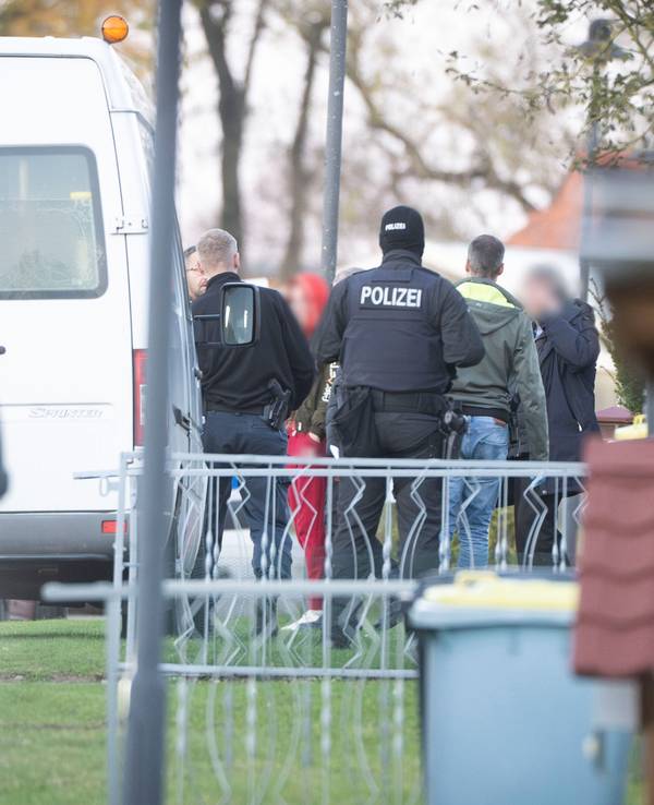 Eine tatverdächtige Frau (Mitte l) verlässt in Begleitung von Polizeibeamten ihr Wohnhaus.