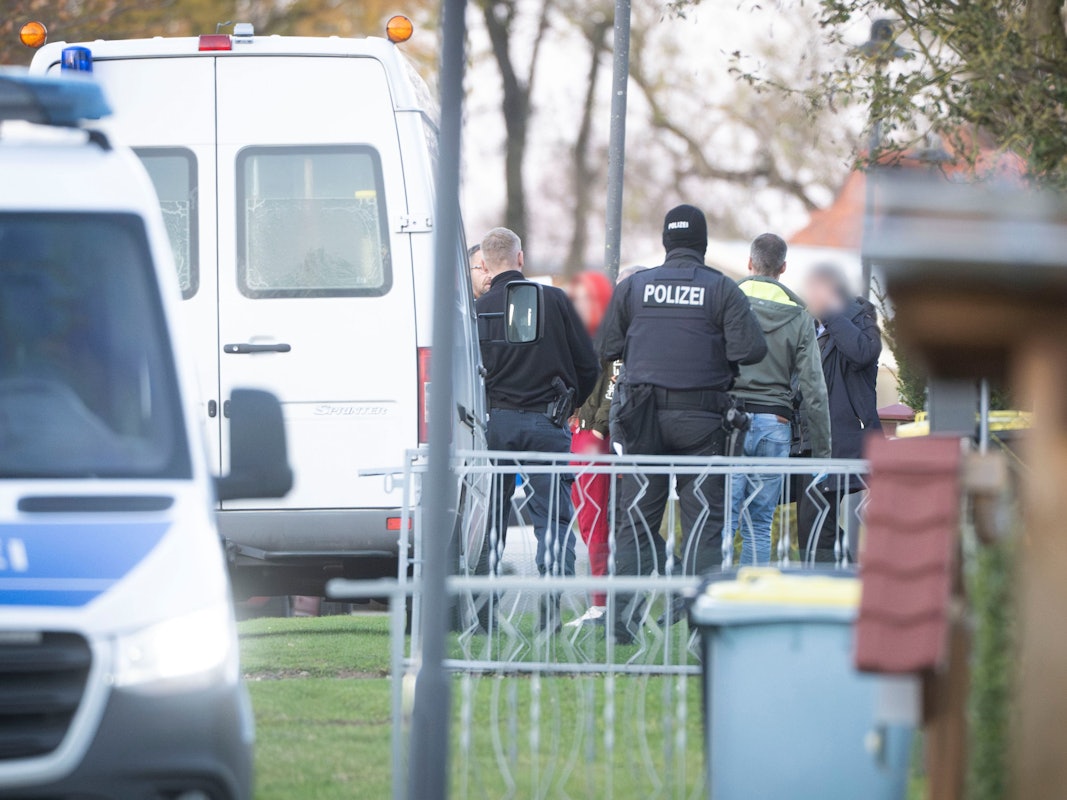 Eine tatverdächtige Frau (Mitte l) verlässt in Begleitung von Polizeibeamten ihr Wohnhaus.