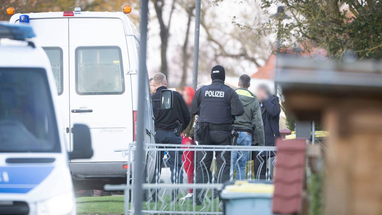 Eine tatverdächtige Frau (Mitte l) verlässt in Begleitung von Polizeibeamten ihr Wohnhaus.